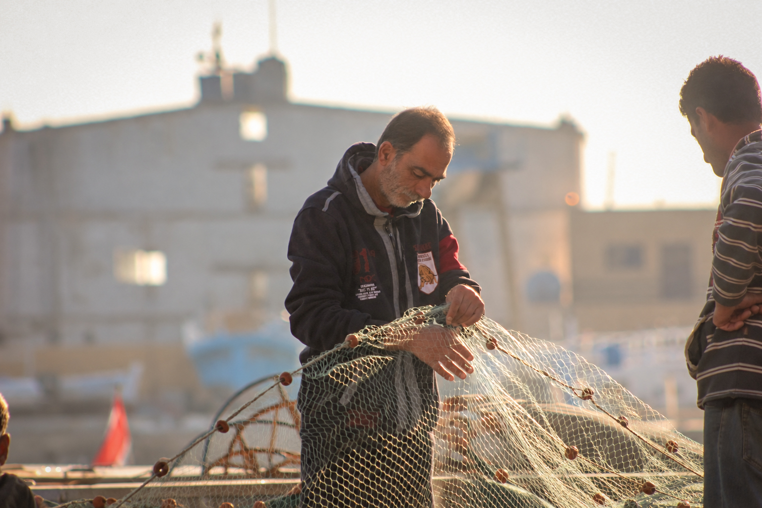 Deux pêcheurs au travail sur un filet, au port