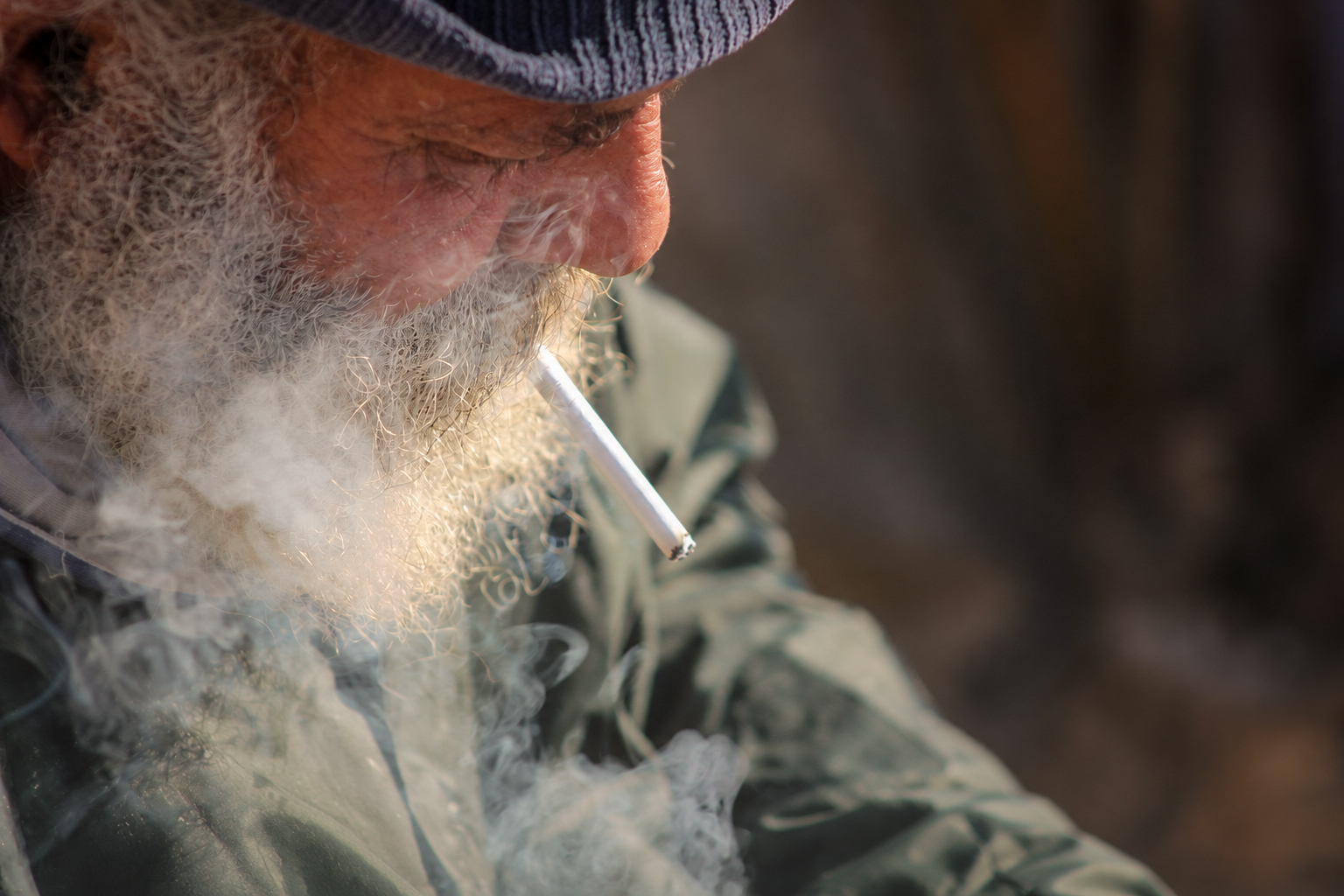 Un pêcheur à la barbe blanche, cigarette aux lèvres, de profil